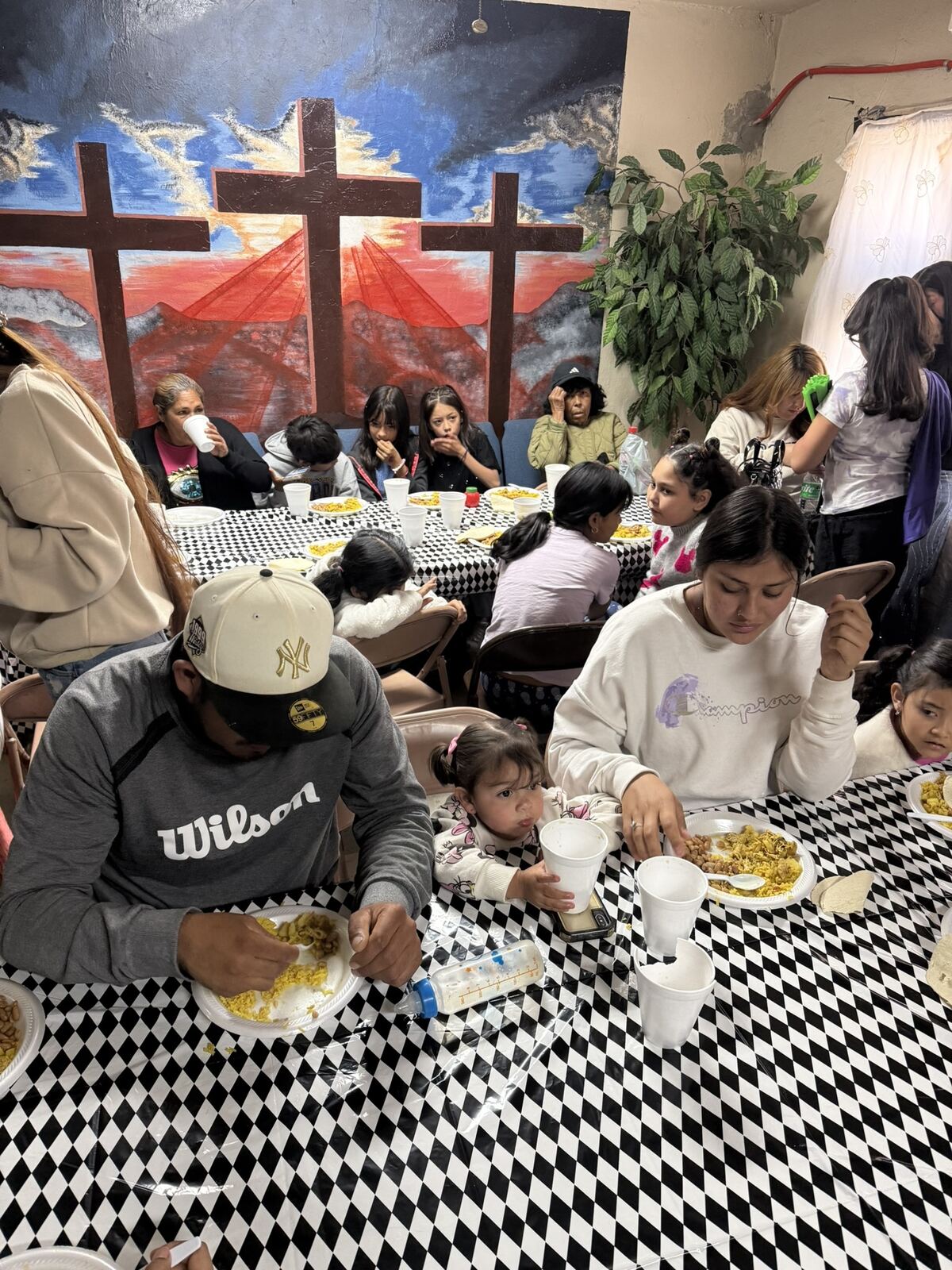 Families seated at long tables sharing a meal inside the church.