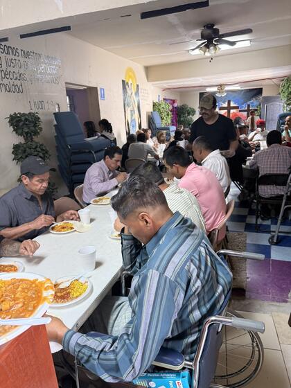 People seated at long tables eating a hot meal inside the church.